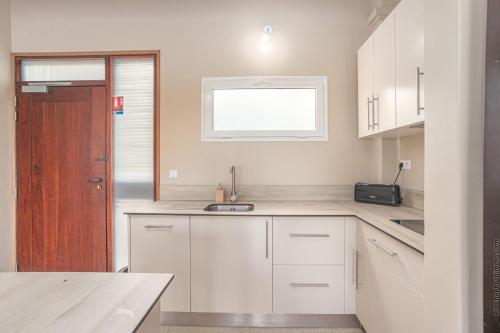 a kitchen with white cabinets and a sink and a window at Les Villas du Lagon in Le François