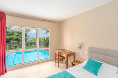 a bedroom with a bed and a desk and a pool at Les Villas du Lagon in Le François