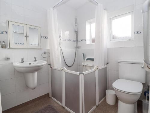 a white bathroom with a toilet and a sink at Ty Cerrig in Rhyl