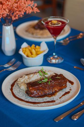 a table with a plate of meat and mashed potatoes and a drink at Del Mar Hotel in Aracaju