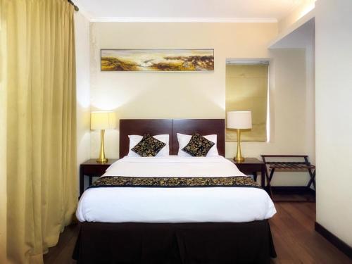 a bedroom with a large white bed with two lamps at Ancol Marina Residence in Jakarta