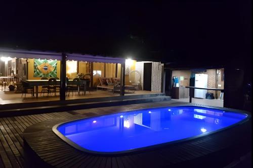 una gran piscina azul frente a una casa por la noche en Aconchego Itaipava, en Petrópolis
