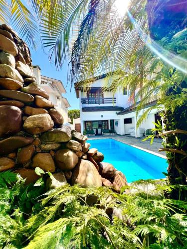 a villa with a swimming pool and a building at Linda Casa com Piscina no Jd. Acapulco-Guarujá in Guarujá