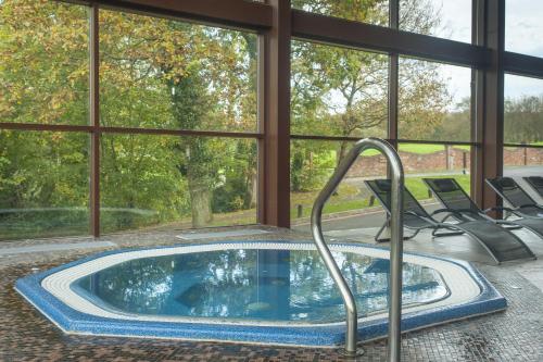 a jacuzzi tub in a room with windows at Woodbury Park Hotel & Spa in Exeter