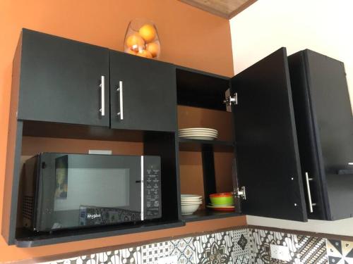 a kitchen with black cabinets and a microwave at Departamento H González 2 in El Coco