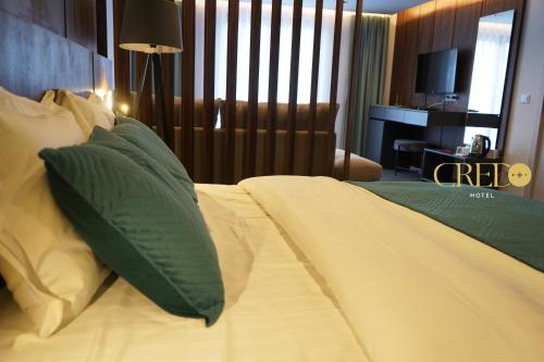 Schlafzimmer mit einem Bett mit grünen und weißen Kissen in der Unterkunft Hotel Credo in Prizren
