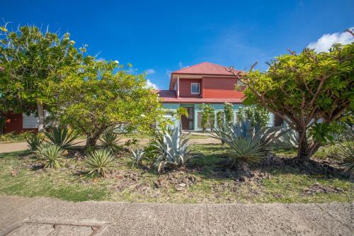 a red house with trees in front of it at Les Villas du Lagon in Le François