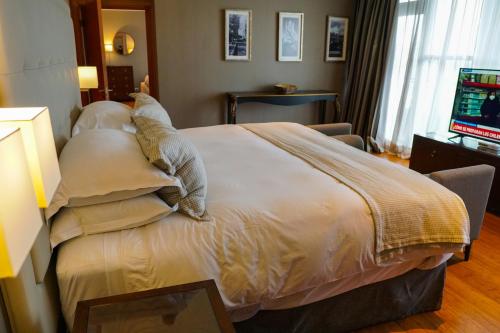 a hotel room with a bed with pillows and a television at Hotel Parada Linares in Linares