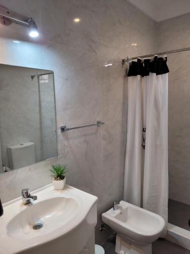 a white bathroom with a sink and a shower at Apartamento en el centro de Lomas in Lomas de Zamora
