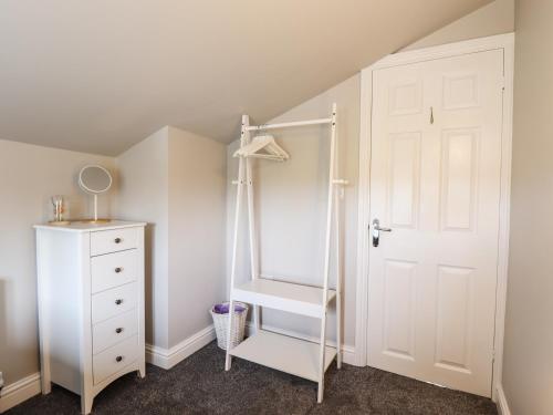 a white closet with a ladder next to a white dresser at Printers Cottage in Alford