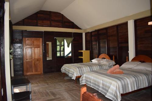 two beds in a room with wooden walls at Eco Aldea kinich Ahau in Xpujil