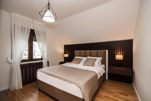 sypialnia z dużym łóżkiem i oknem w obiekcie Villa Inverno & Spa w mieście Kolašin