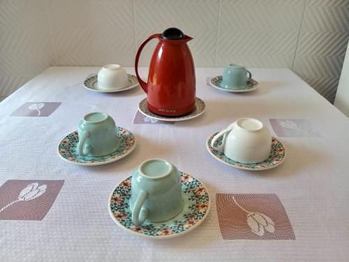 uma mesa com chávenas e pires com um bule de chá em Casa da Thalita em Pirenópolis