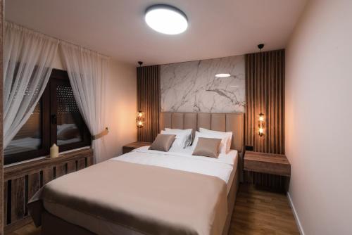 a bedroom with a large white bed and two windows at Villa Inverno & Spa in Kolašin