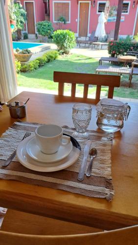 uma mesa com um copo e um prato sobre uma mesa em Pousada Casa da Aroeira em Búzios