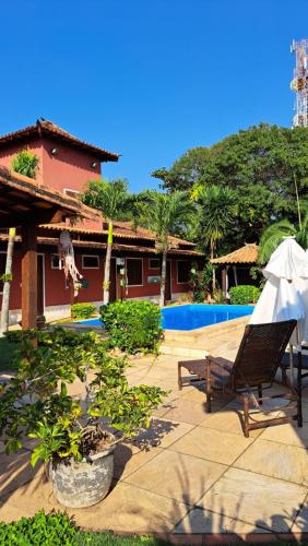 a resort with a pool and a chair and a umbrella at Pousada Casa da Aroeira in Búzios