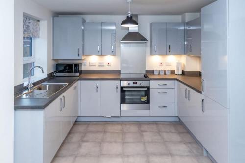 una cocina blanca con armarios blancos y fregadero en Cozy 3 bed Sasha house in Beeston Nottingham, en Nottingham