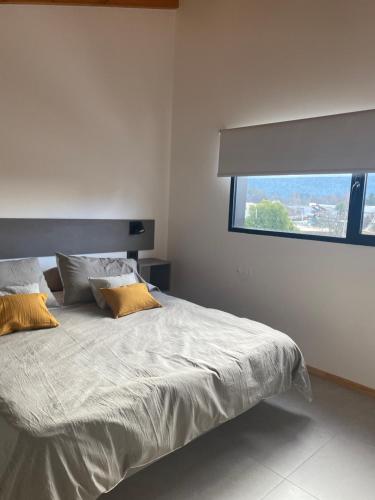 a bedroom with a bed with two pillows and a window at ENTREVERDES Departamentos in El Bolsón