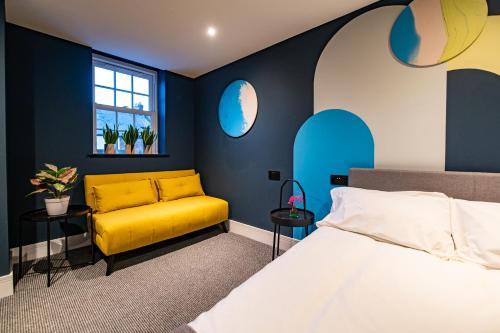 a bedroom with a yellow couch and blue walls at The Nest - Luxury 16 person Apt w jacuzzi & parking in Blackpool