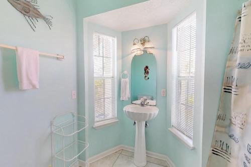 a white bathroom with a sink and two windows at Southern Belle in St. George Island