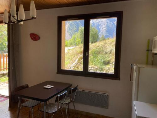a dining room with a table and a window at Vénosc-Les 2 Alpes , Rez de jardin in Vénosc