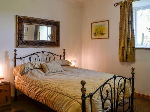 a bedroom with a bed with a mirror on the wall at Church Cottage in Rigg