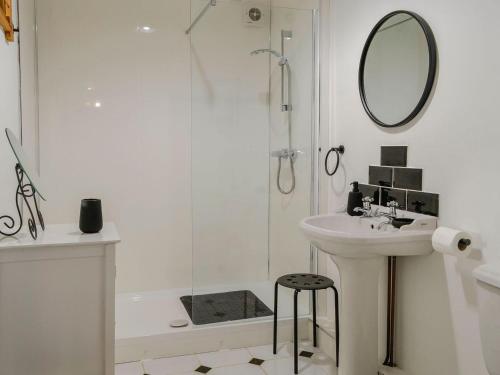 a white bathroom with a sink and a mirror at Church Cottage in Rigg