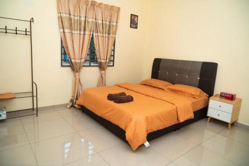 a bedroom with a large bed with an orange blanket at Adorable 2-bedroom home with Wi-Fi, Netflix and BBQ grill in Rembau