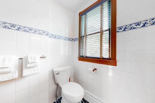 a white bathroom with a toilet and a window at Sweet Berry Farm in Jamaica