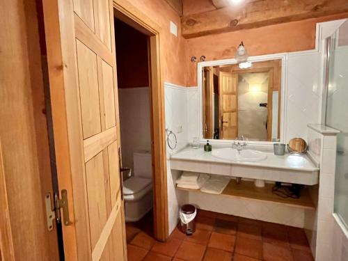 a bathroom with a sink and a toilet and a mirror at Saltus Alvus, casas 4 estrellas con encanto en Sotosalbos in Sotosalbos