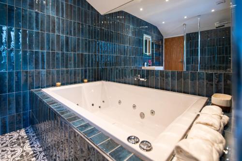 a bath tub in a bathroom with blue tiles at The Nest - Luxury 16 person Apt w jacuzzi & parking in Blackpool