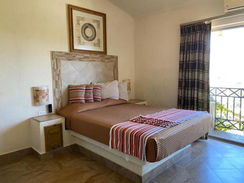 1 dormitorio con 1 cama grande y ventana en Cabo Vista Hotel Adults Only, en Cabo San Lucas