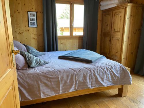 a bedroom with a bed with a blue blanket and a window at Chalet Alpilles - Chalet familial, récent, tout équipé in Chamoson