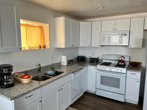 una cocina con armarios blancos y un horno de fogón blanco en Perfect Little Place en Tooele