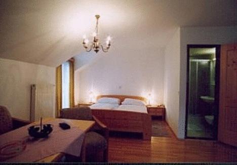 a bedroom with a bed and a table and a chandelier at Hotel & Hostel Sandwirt in Bad Ischl