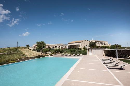 a swimming pool with lounge chairs and a house at La Dimora di Spartivento - BW Signature Collection in Ragusa