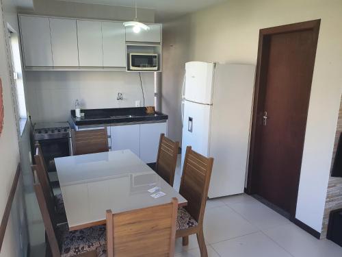 una cucina con tavolo e frigorifero bianco di Duplex com vista do mar! a Itapema