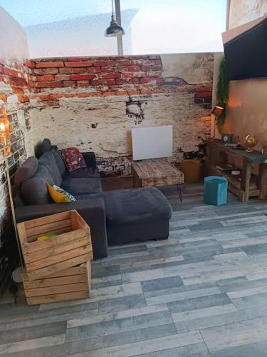 a living room with a couch and a brick wall at Dormir à l'usine Loft industriel Atypique in Saint-Quentin-Lamotte-Croix-au-Bailly