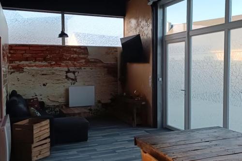 a living room with a brick wall and a table at Dormir à l'usine Loft industriel Atypique in Saint-Quentin-Lamotte-Croix-au-Bailly