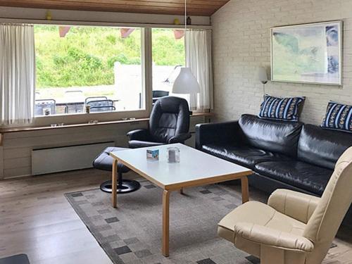 a living room with a black leather couch and a table at 6 person holiday home in Aabenraa in Aabenraa