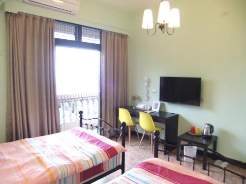 a hotel room with a bed and a desk and a window at Jiufen Hui Ming Homestay in Jiufen