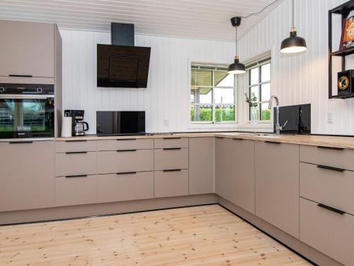 uma cozinha com armários brancos e piso em madeira em 4 person holiday home in Juelsminde em Juelsminde