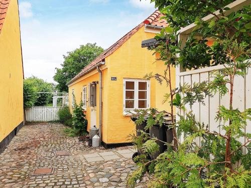 une maison jaune avec une passerelle en pierre devant elle dans l'établissement 4 person holiday home in S by, à Sæby