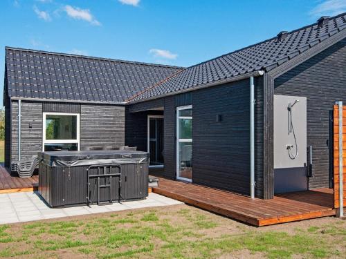 a black house with a deck and a grill at 12 person holiday home in Ansager-By Traum in Ansager