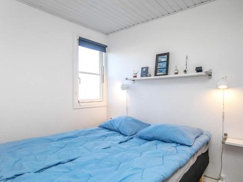 a bed with blue pillows in a room with a window at Apartment Vestervig III in Vestervig