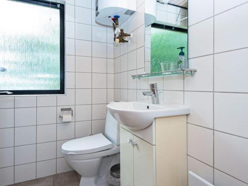a white bathroom with a toilet and a sink at Holiday home Skanderborg V in Skanderborg