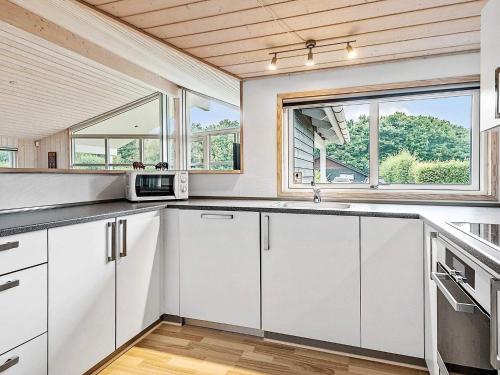 a kitchen with white cabinets and a large window at 8 person holiday home in Ansager in Ansager