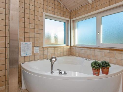 La salle de bains est pourvue d'une baignoire et de 2 plantes en pot. dans l'établissement 6 person holiday home in Tarm, à Tarm