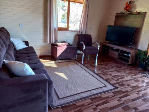uma sala de estar com um sofá e uma televisão de ecrã plano em Refúgio Santo Antônio em Urubici