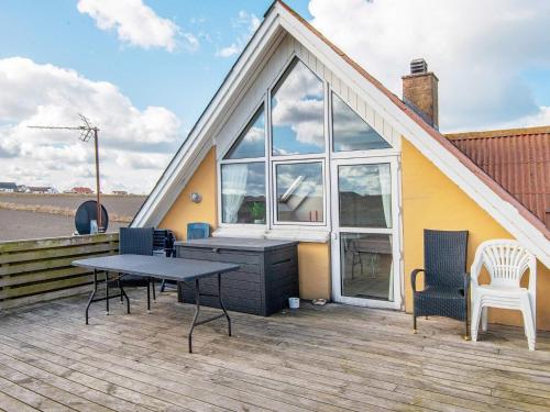 a house with a table and chairs on a deck at 12 person holiday home in Lemvig in Ferring